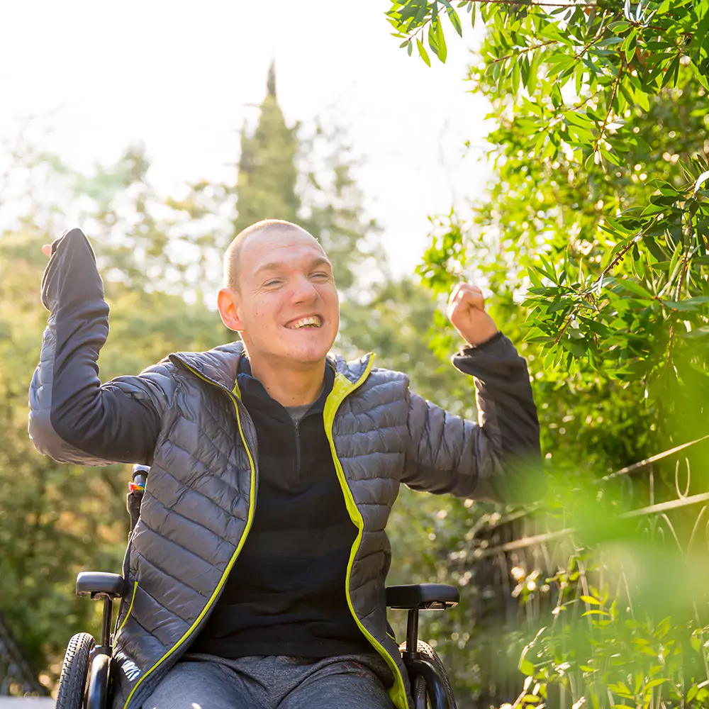 Happy disabled man smiling while sitting in a wheelchair in the park