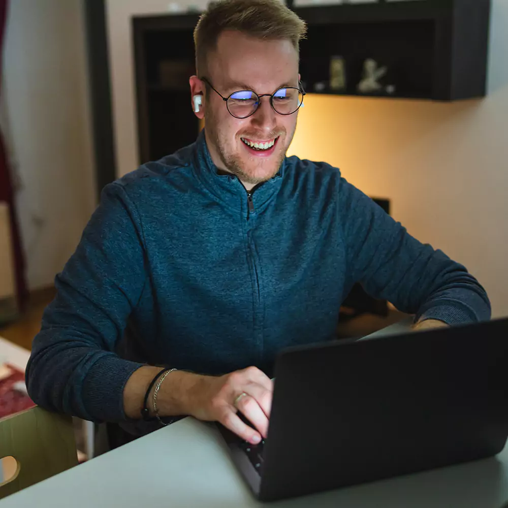 Man smiling while having a meeting on his laptop